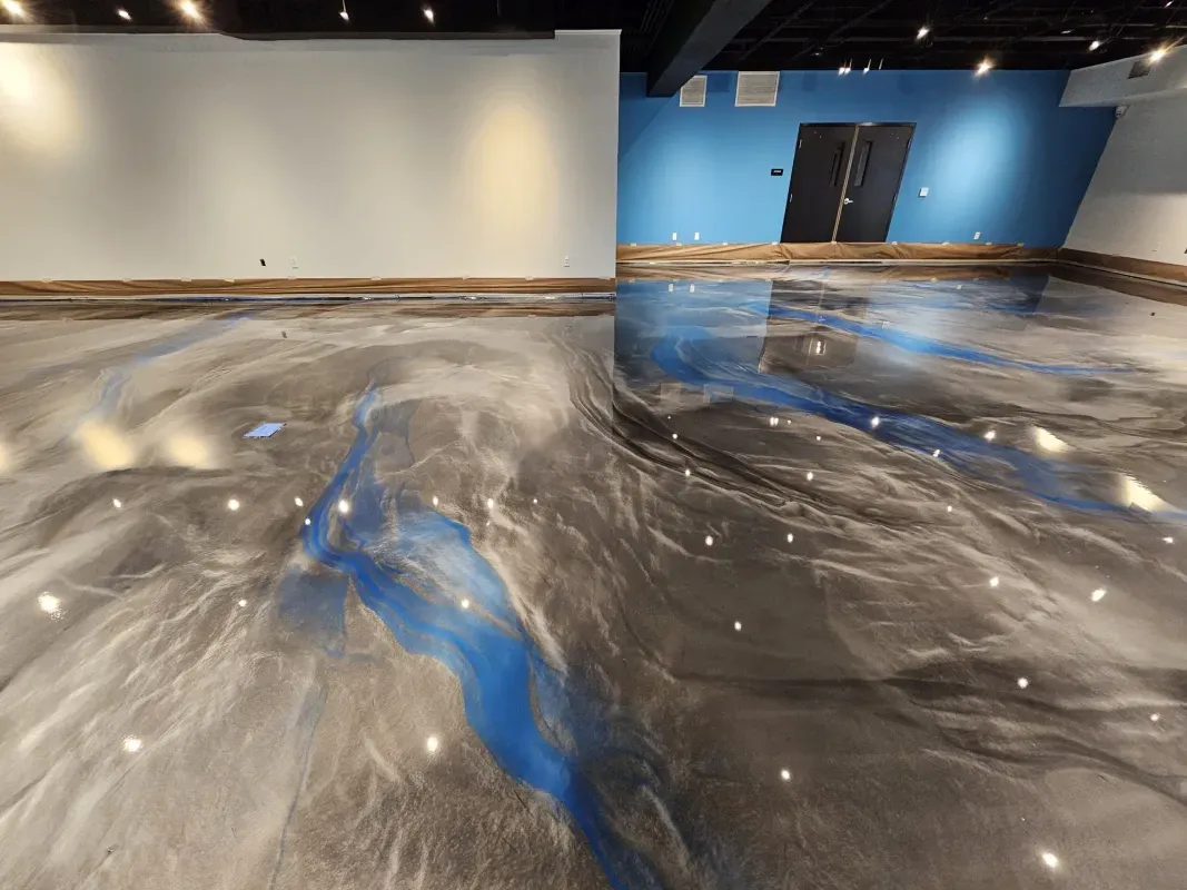 Abstract black, white, and blue swirled epoxy floor in a large empty room