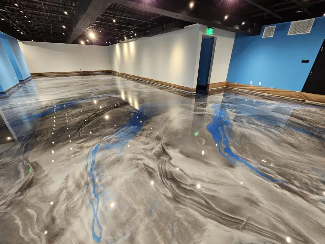 Empty gallery room with a glossy blue, gray, and white marbled floor and blue accent walls