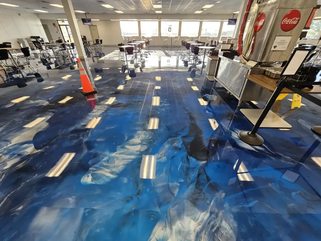 Workshop with blue floor covering, scattered tools, and furniture being moved or repaired.