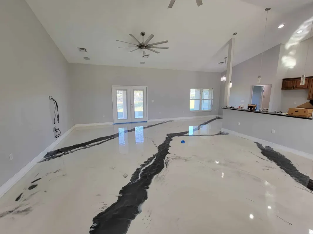 Bright open-plan kitchen and living room with white walls, marble floor, ceiling fan, and large windows