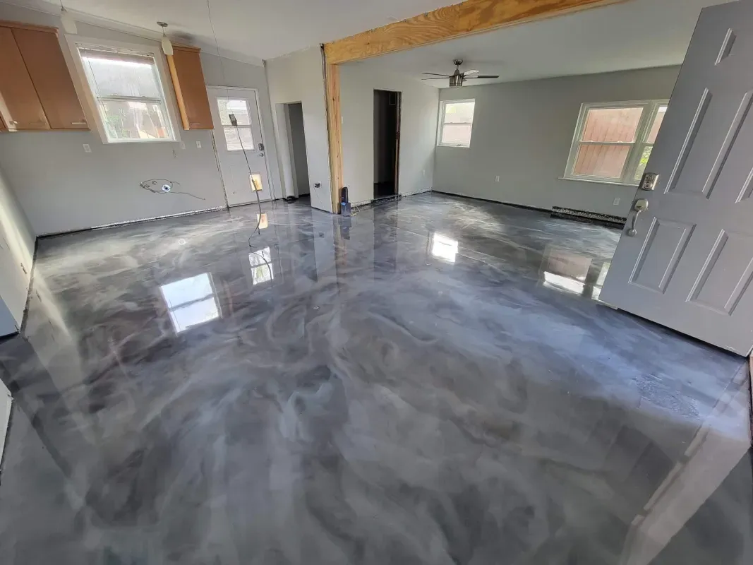 Empty room with glossy gray floor, open doorway, and large wall mirror