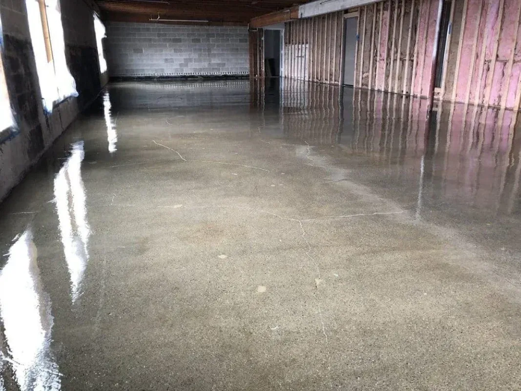 Empty flooded basement with standing water and concrete floor reflections