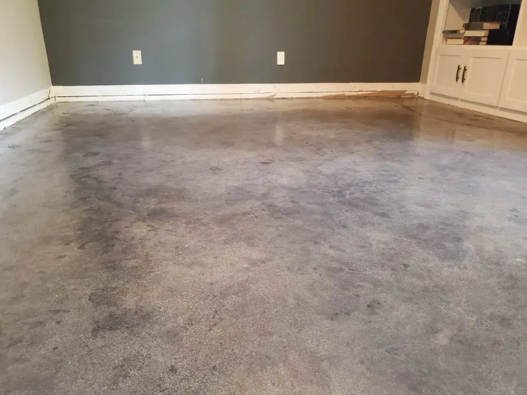 Empty gray-carpeted room with dark gray accent wall and white built-in cabinet.