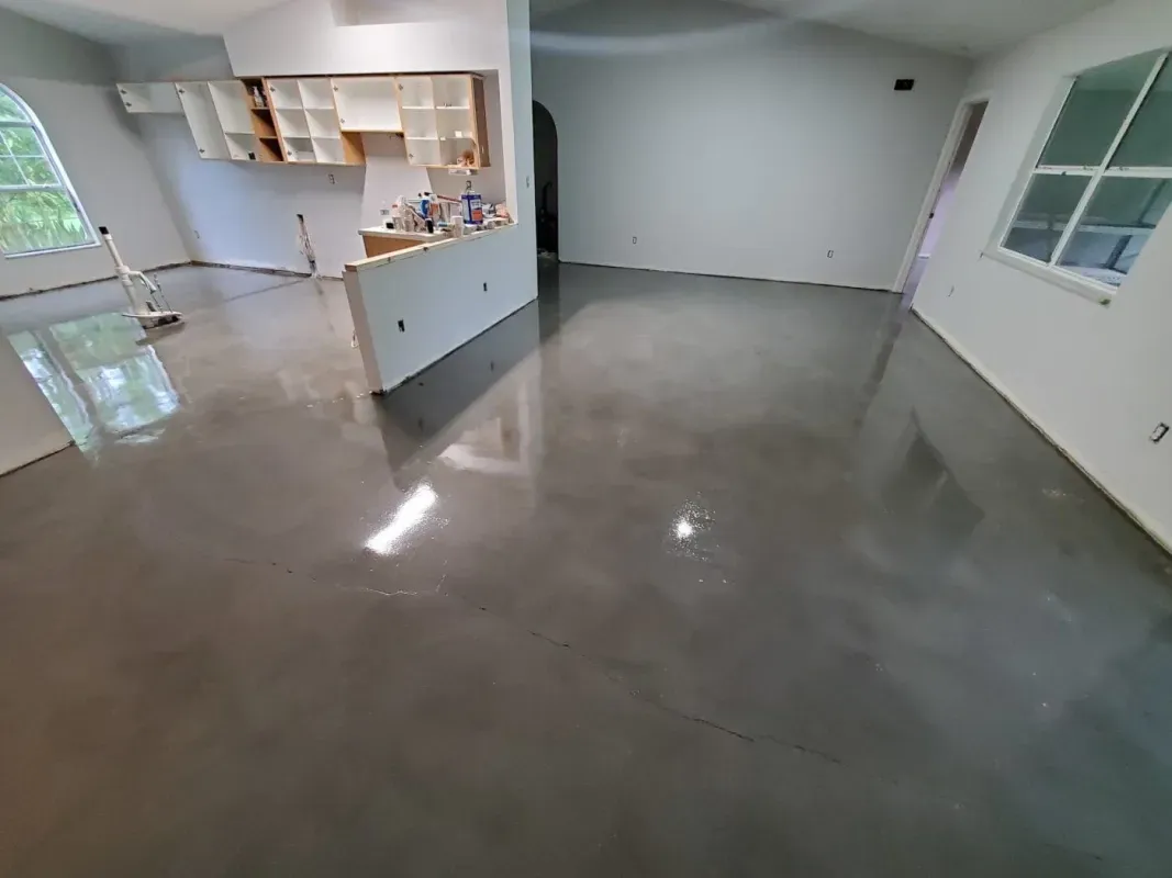 Empty modern room with polished concrete floor, white walls, kitchen pass-through, and windows.