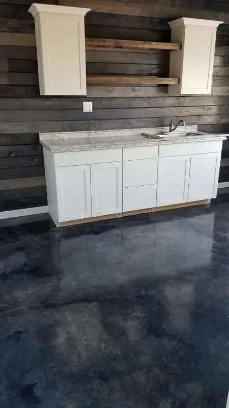 White cabinets and shelving installed on a dark wood-paneled wall in a garage or workshop.