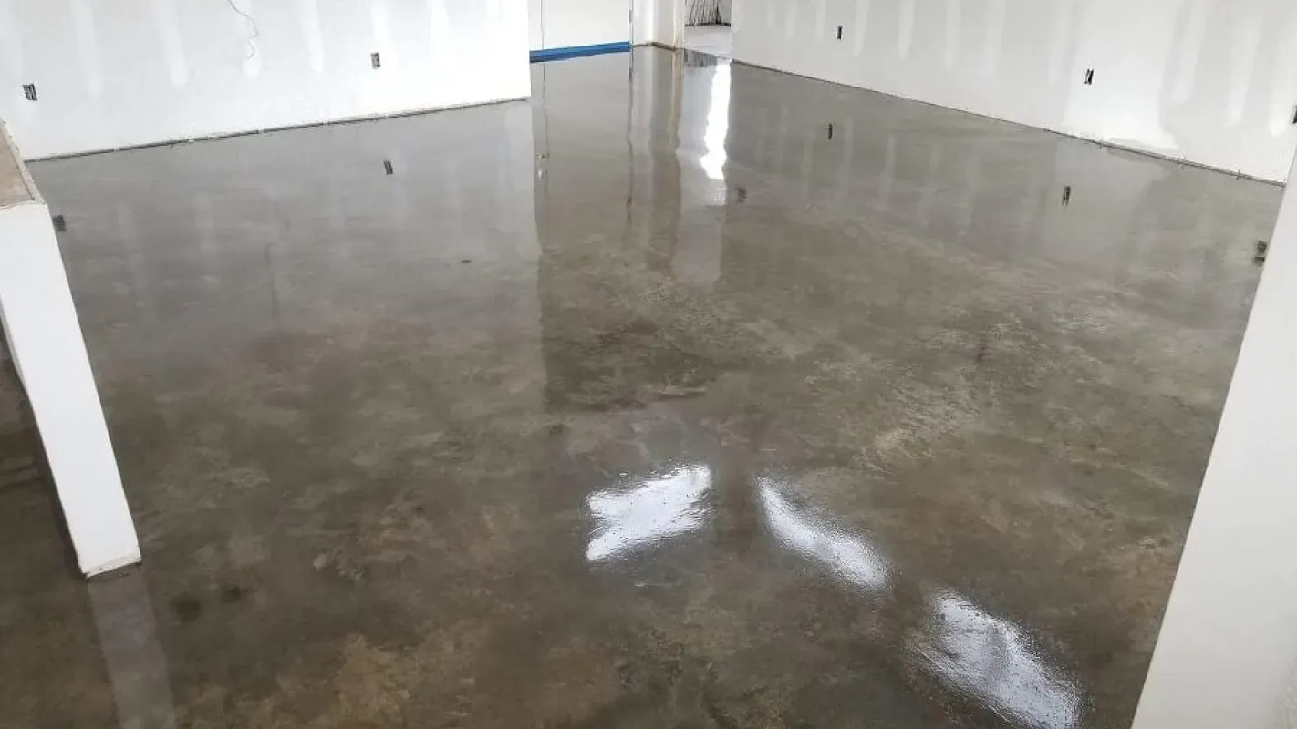Empty room with glossy gray floor and white walls reflecting light, viewed through an open doorway