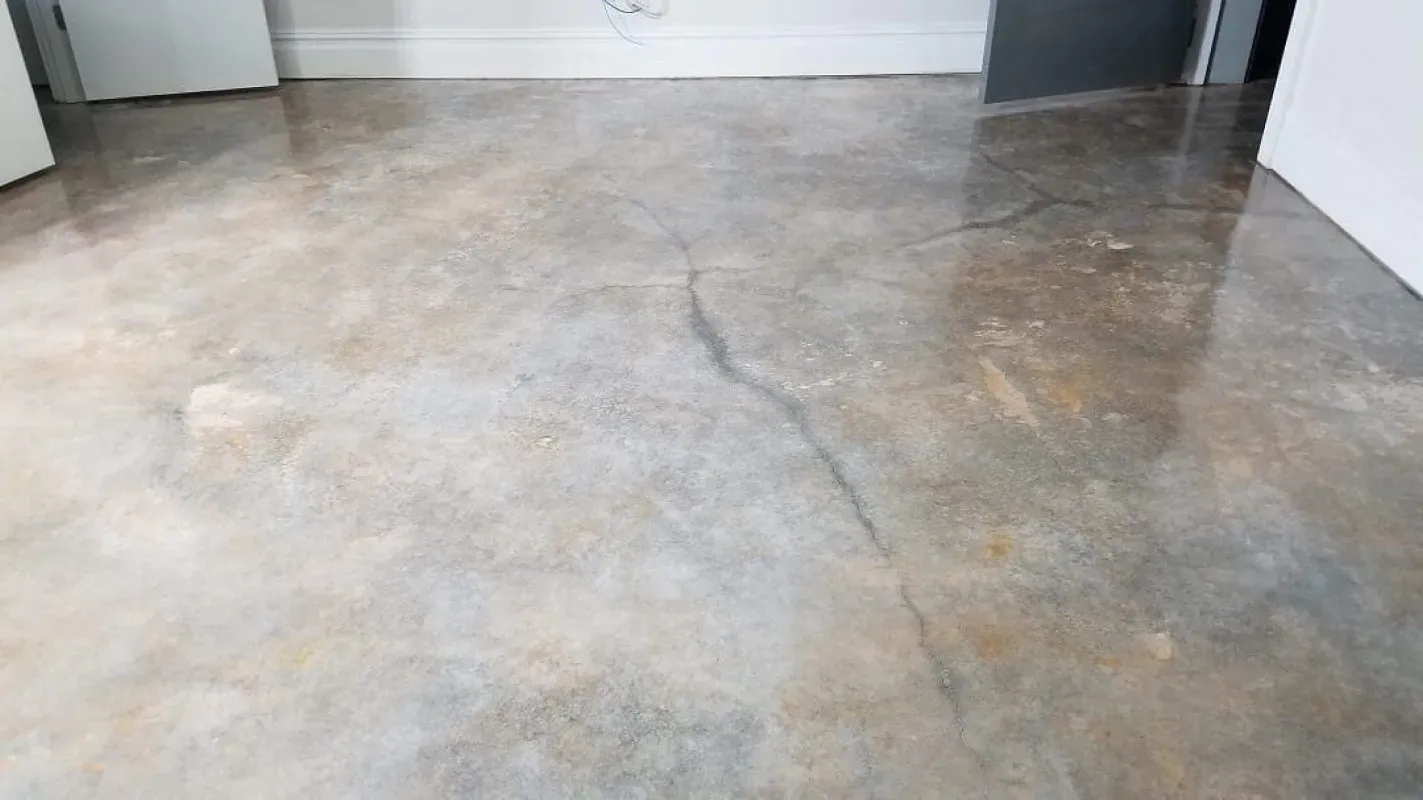 Bare concrete floor in an empty room with a visible crack and gray walls.