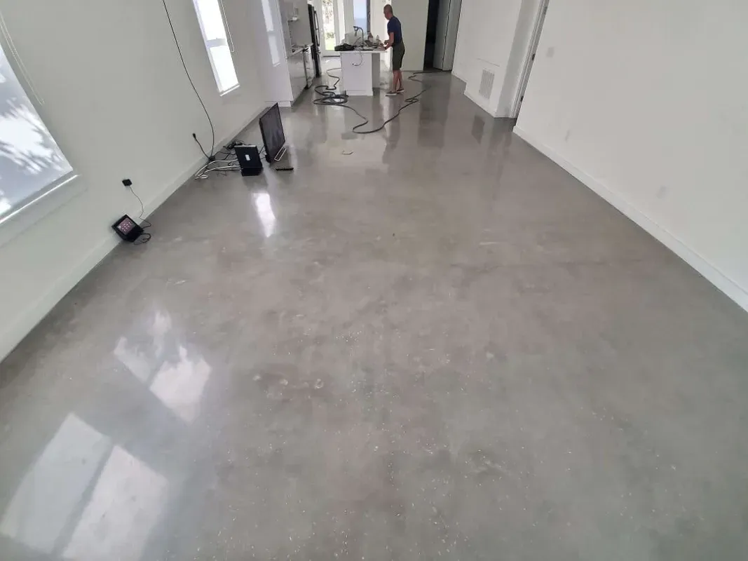 Bright hallway with glossy gray floor, white walls, and cleaning equipment near the far end