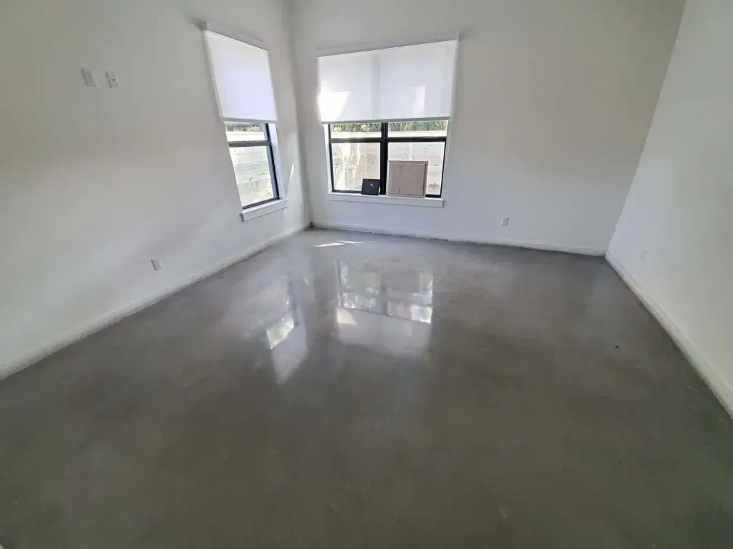 Empty white room with glossy concrete floor and two windows letting in natural light