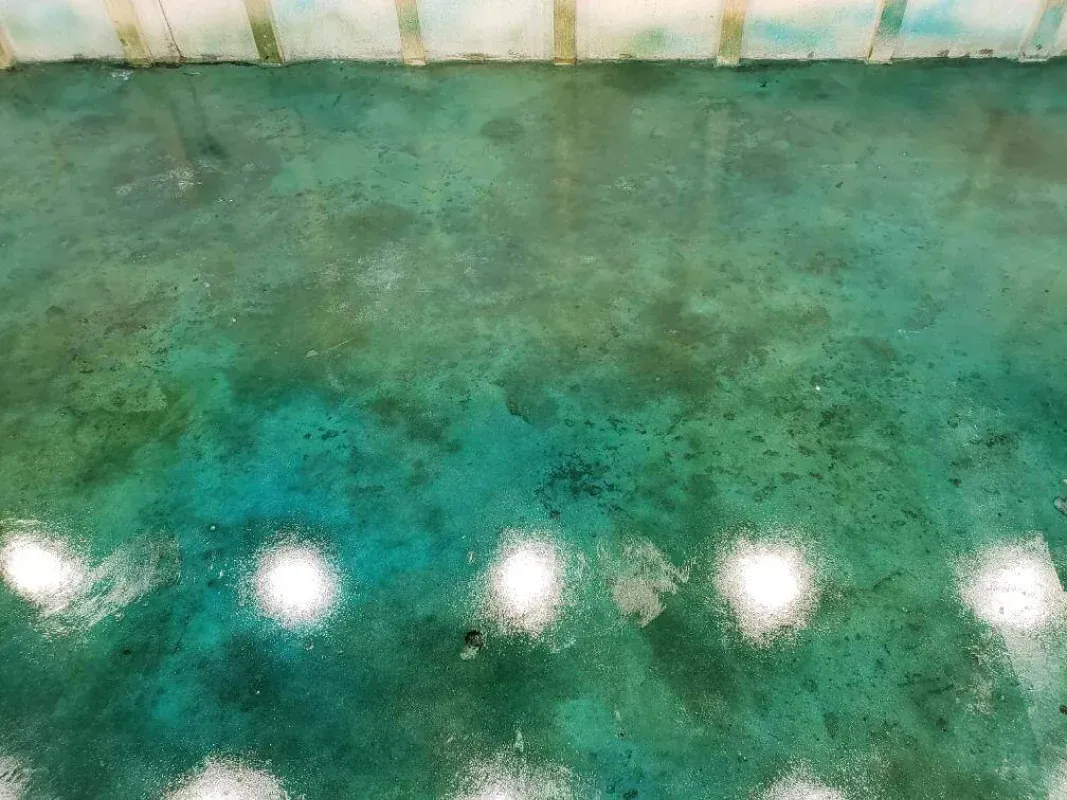 Green-blue marble countertop with white overhead light reflections and a beige backsplash edge