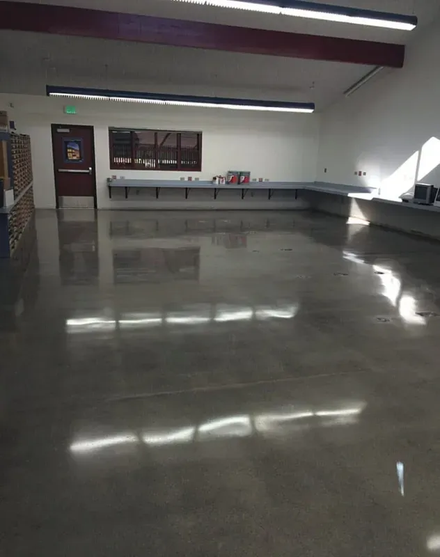 Empty indoor hall with glossy floor, long tables, and fluorescent lights