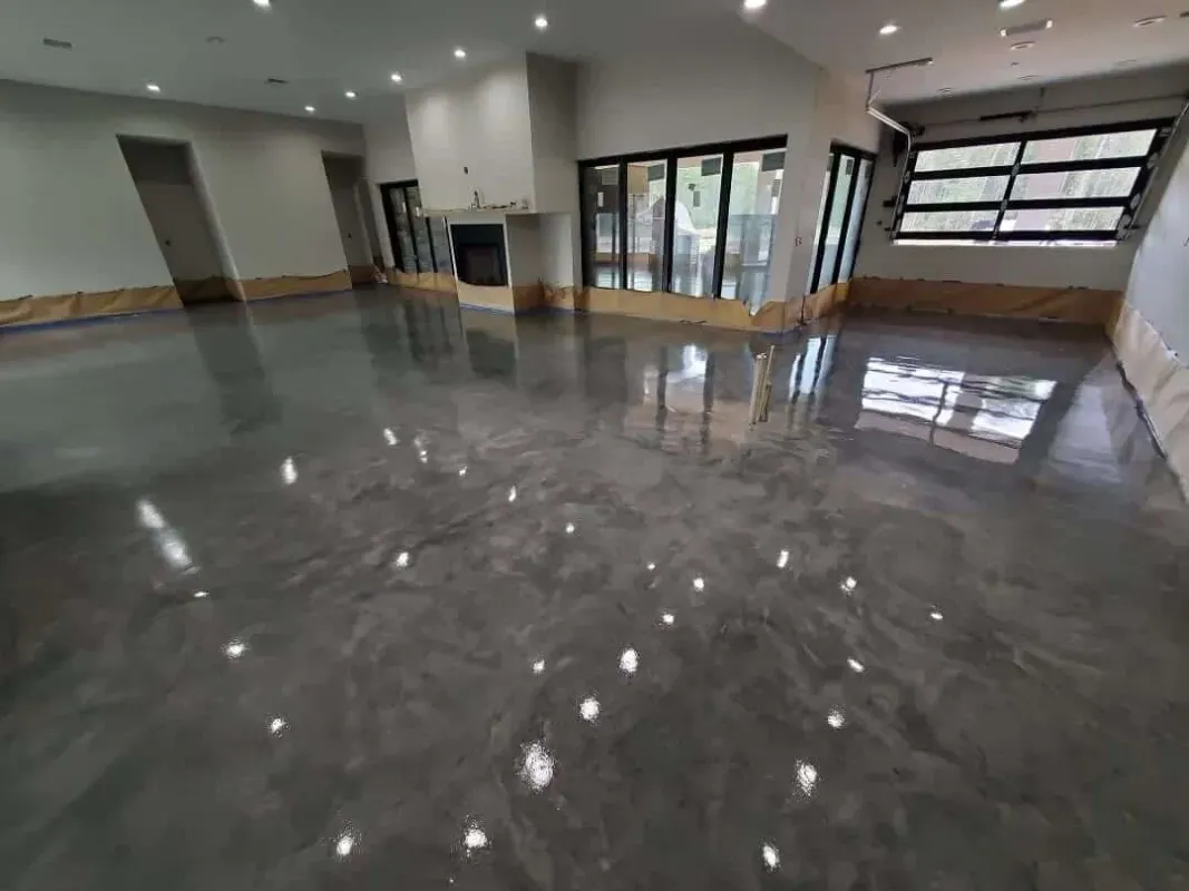 Empty modern room with glossy gray floor, white walls, and large windows letting in daylight