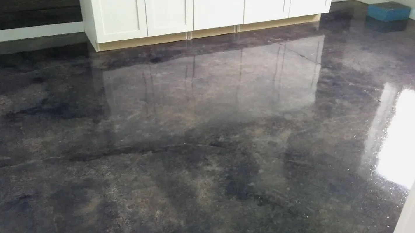 Shiny dark marble floor in a room with white cabinets along the wall