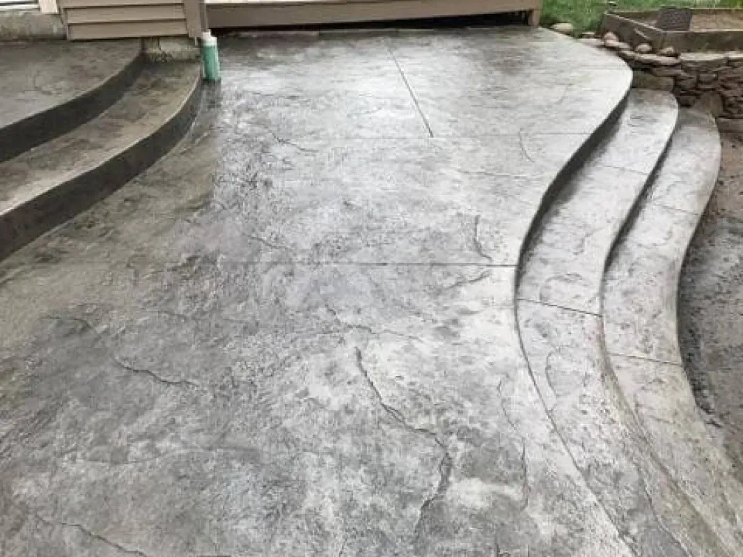 Stamped concrete walkway with curved steps leading to a wooden deck entrance