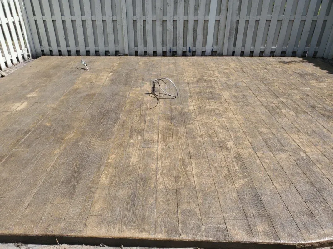 Empty weathered wooden deck against a white picket fence
