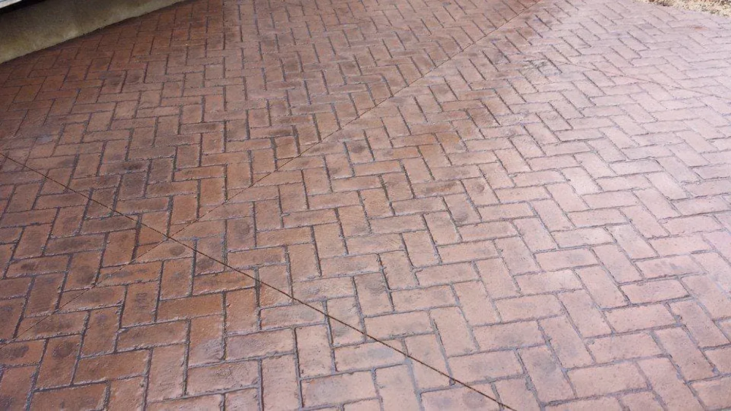 Pinkish brick pavement in a herringbone pattern, viewed close up.