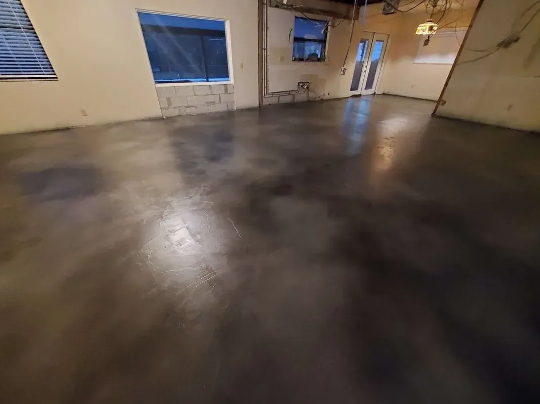 Empty room with polished concrete floor, beige walls, and windows letting in light