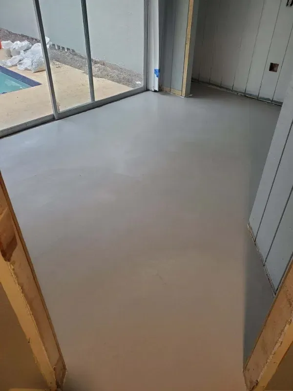 Empty room with smooth gray floor and sliding glass doors to a patio
