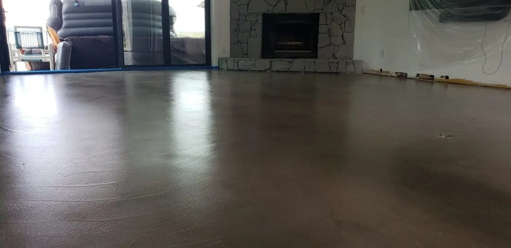 Empty polished floor in a dim room with a fireplace and bright doorway in the background