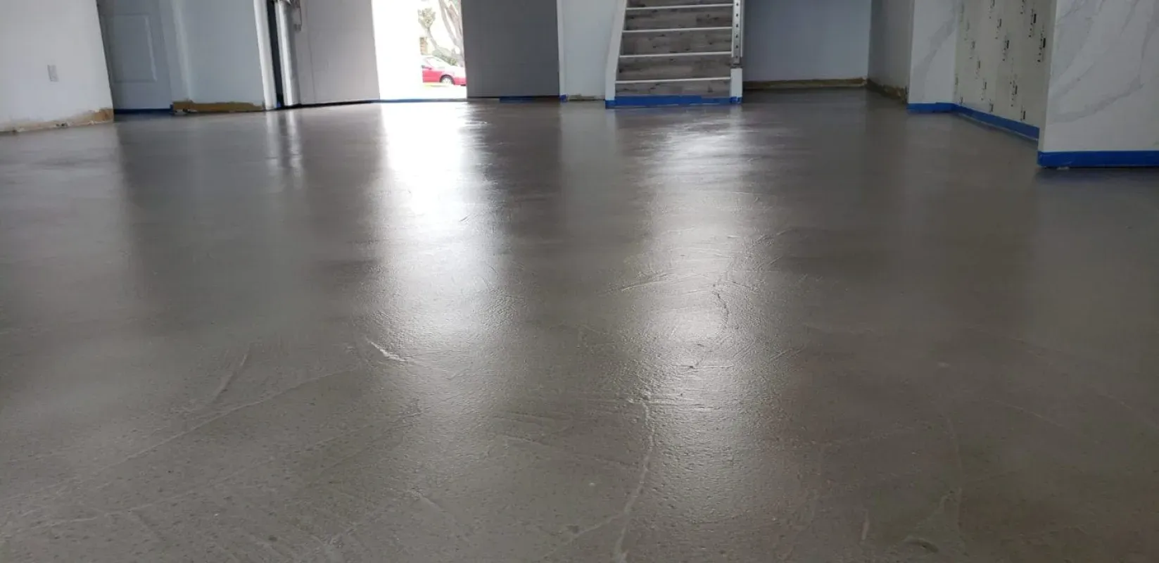Empty indoor room with gray floor, white walls, and stairs in the background