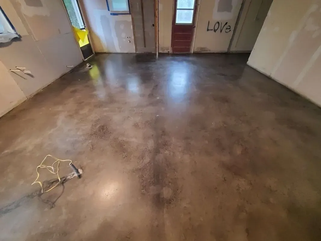 Empty room with stained concrete floor, white walls, and a few scattered cords near the left side.