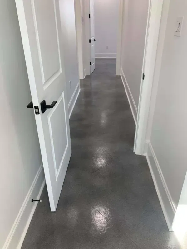Narrow white hallway with open doors and gray polished floor.