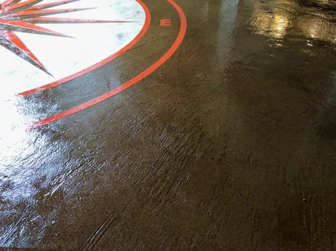 Glossy dark concrete floor with a red-and-white curved painted design in the corner