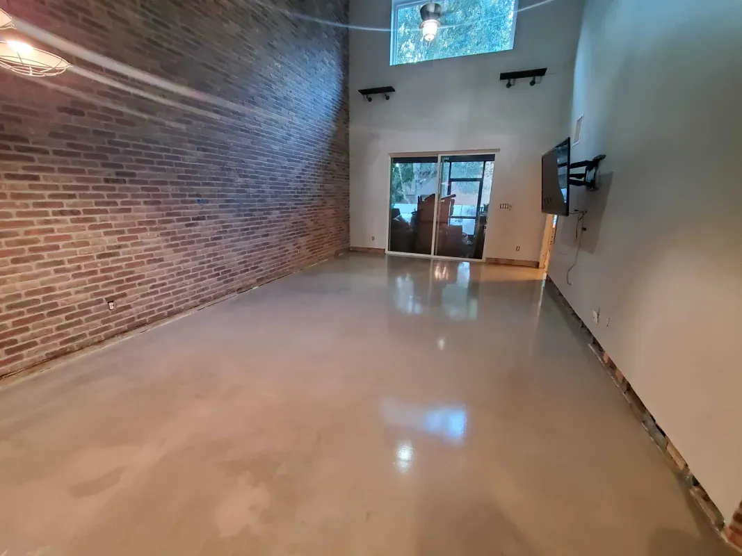 Empty modern hallway with glossy floor, exposed brick wall, and glass doors at the end
