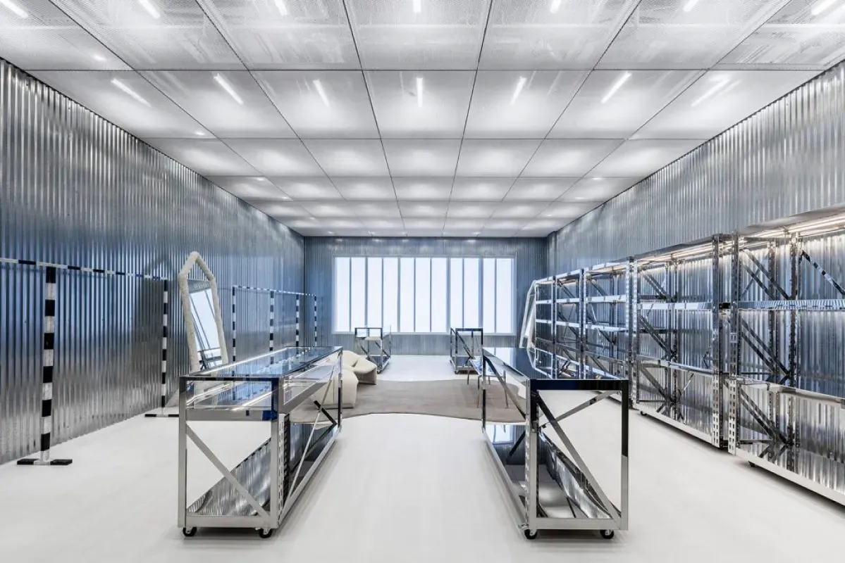Bright modern industrial room with metal shelving, tables, and a large window at the end
