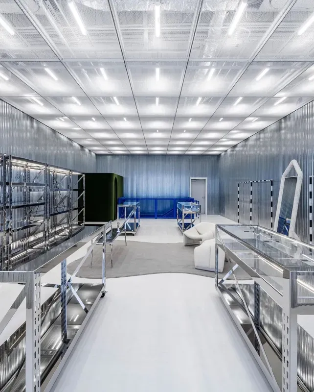 Bright industrial lab with stainless steel workbenches, shelving, and a reflective ceiling under cool lighting