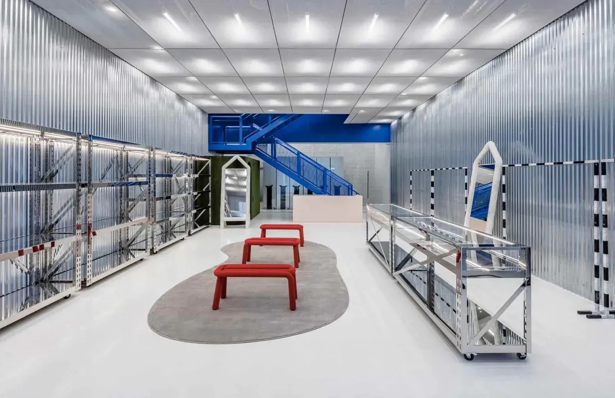 Modern metallic room with two red chairs, glass walls, and racks/display cases along both sides