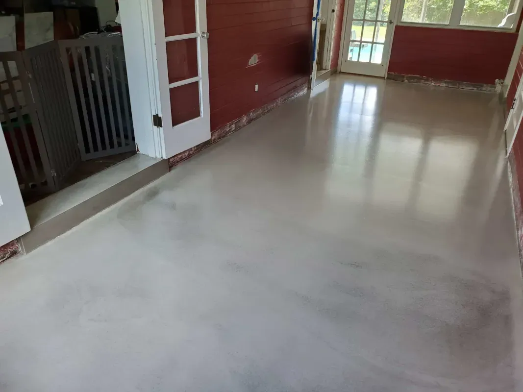 Empty room with glossy white floor, red walls, and large windows letting in daylight
