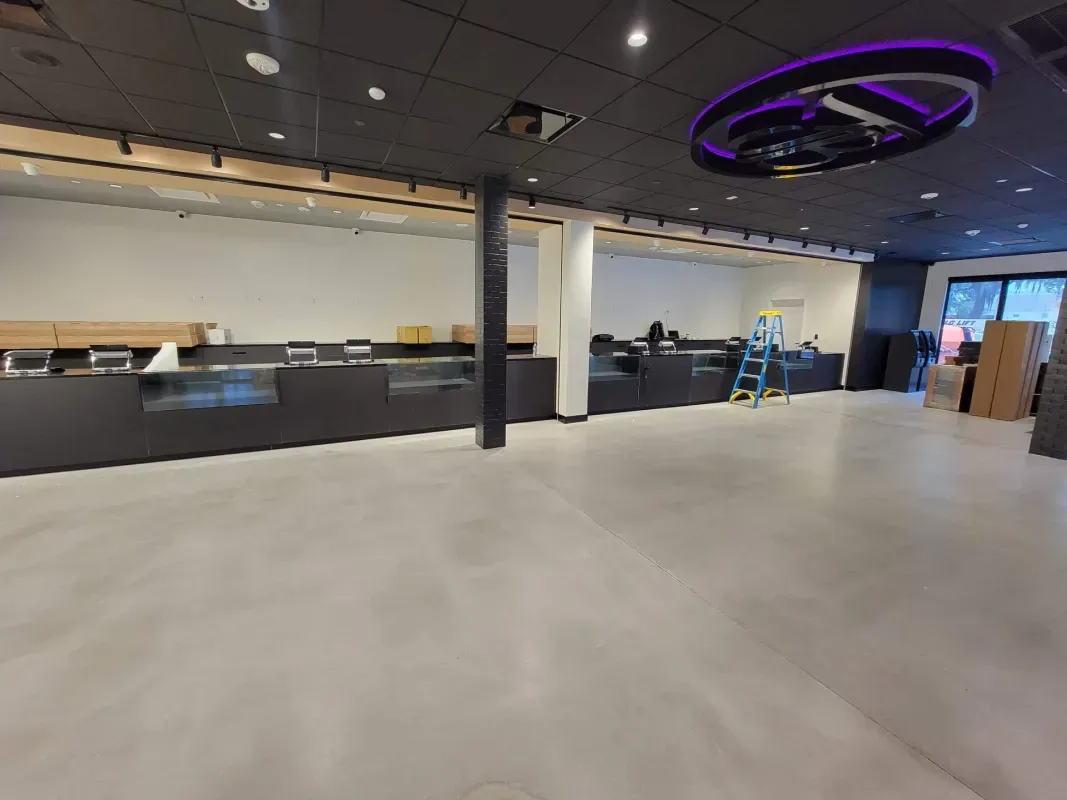 Empty modern office lobby with black counters, gray floor, and purple ceiling light ring