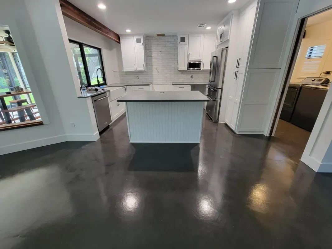 Modern open-plan kitchen with dark floors, white cabinetry, and a center island beneath recessed lighting