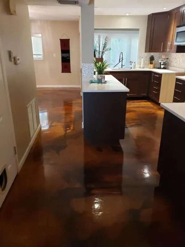 Kitchen with glossy dark floor, island, and sink by a bright window.