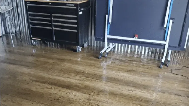 Wooden studio floor with a black tool chest, blue equipment cart, and corrugated metal wall