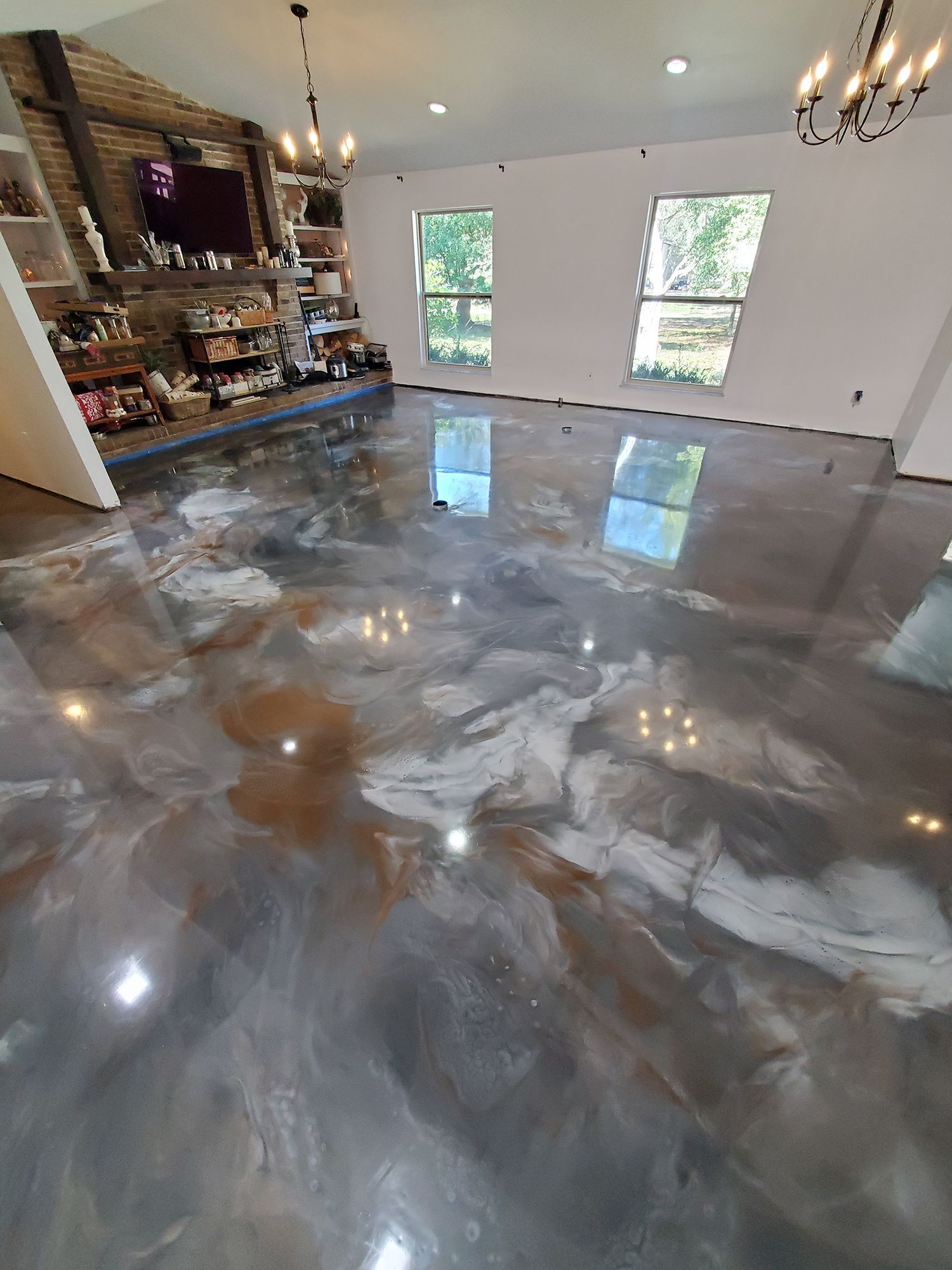 Glossy gray epoxy floor in a modern room with shelves, windows, and sunlight reflections