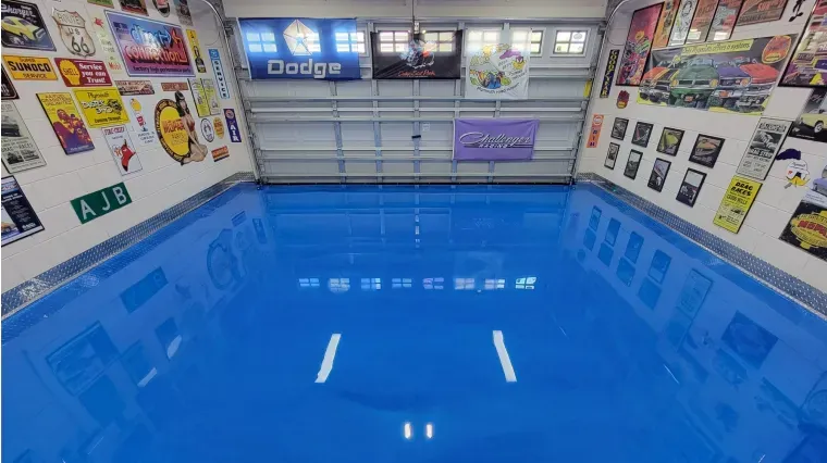 Bright blue polished floor in a garage-like room with posters and signs on the walls and overhead lights.