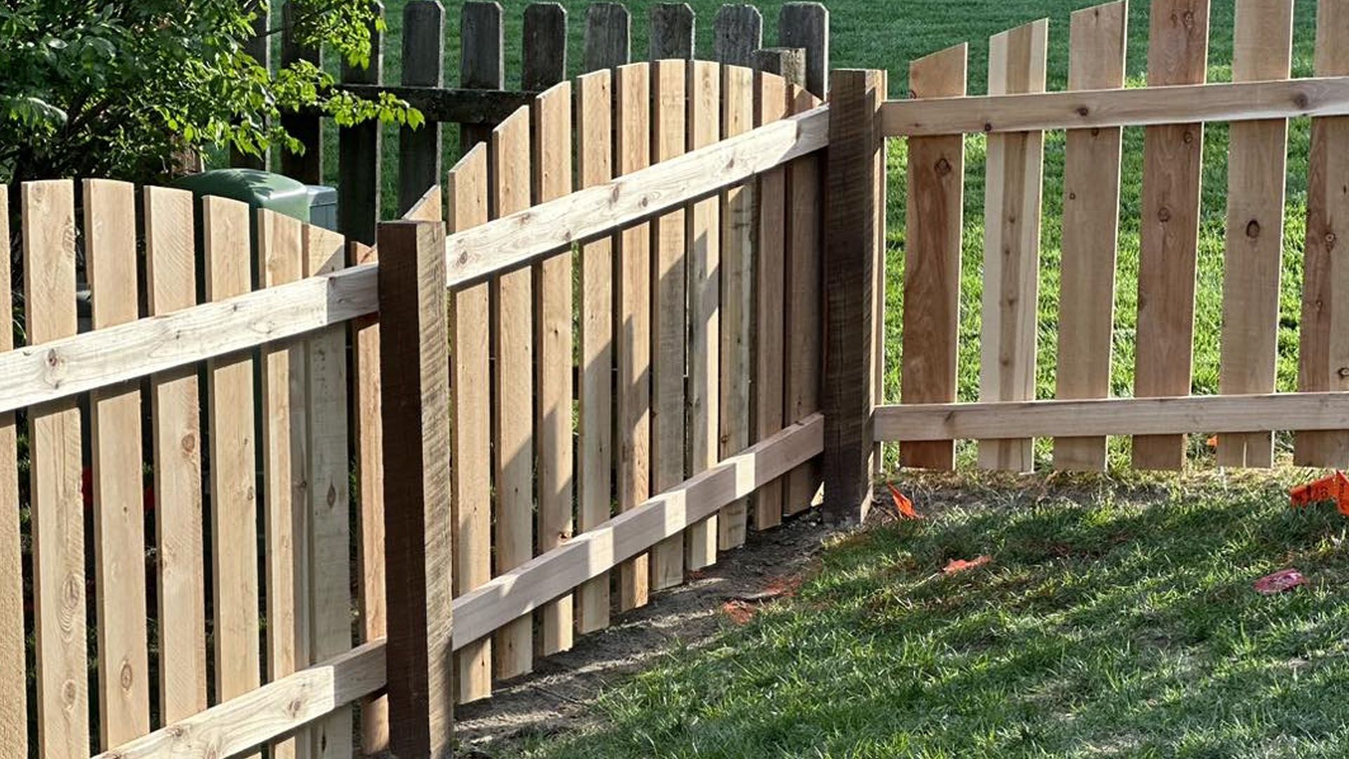 A wooden fence is sitting in the middle of a lush green field.