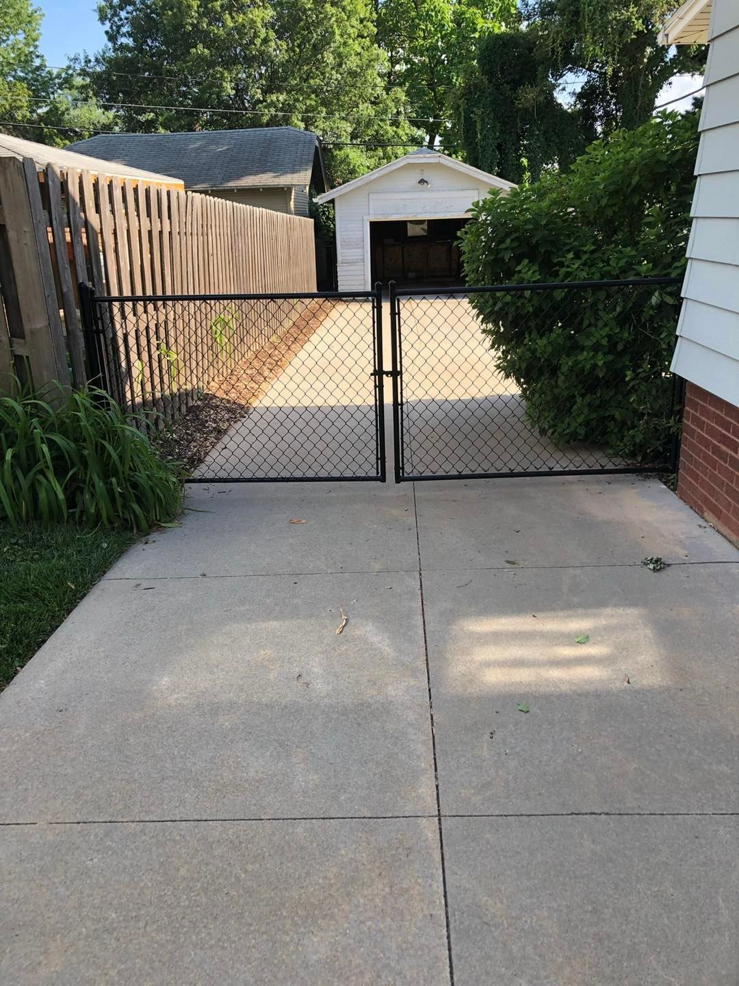 A chain link fence surrounds a driveway leading to a garage.