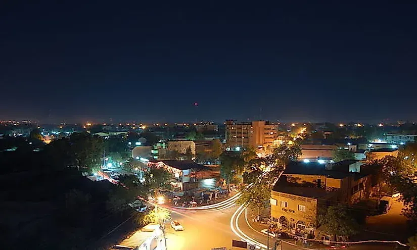 City at night, with lights illuminating streets and buildings under a dark sky.