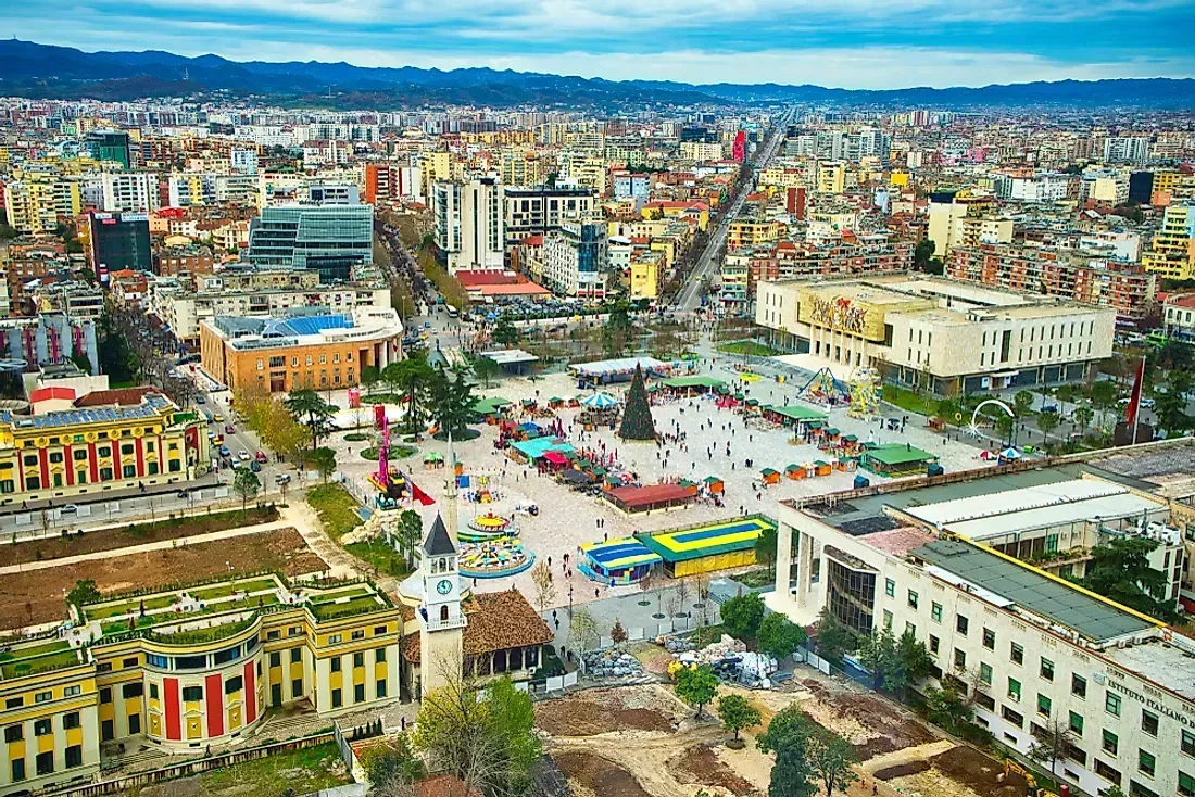 Aerial view of a bustling city square in Quito, Ecuador, with buildings of various heights and a large plaza with people and festive decorations.