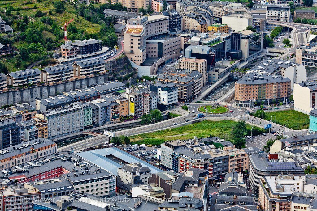 High-angle view of Andorra la Vella, Andorra, a city nestled in a valley. Buildings of various heights and colors fill the urban landscape.