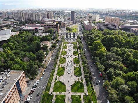 Aerial view of Yerevan, Armenia. A long park with fountains and gardens runs through the city, lined by buildings and green trees.