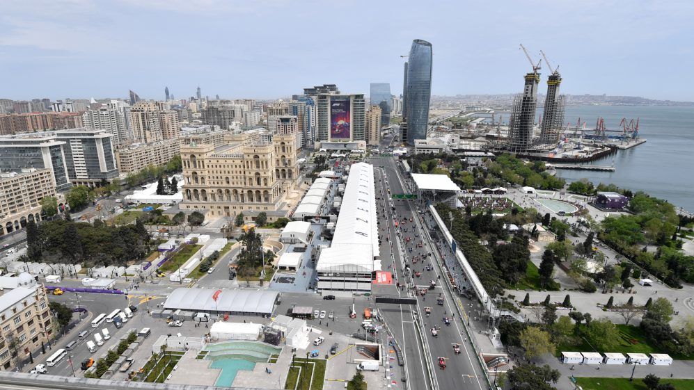 Aerial view of Baku City Circuit, Azerbaijan. A long straightaway with white tents and cityscape backdrop next to the Caspian Sea.