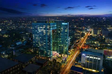 Nighttime cityscape with illuminated skyscrapers and a busy street.