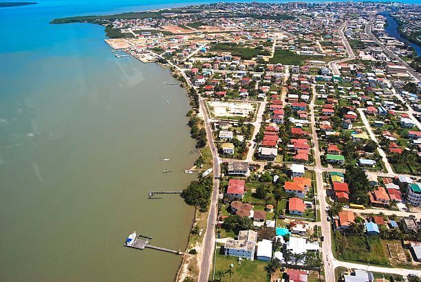 Aerial view of Belize City, Belize, with houses, roads, and coastline along a river leading to the sea.