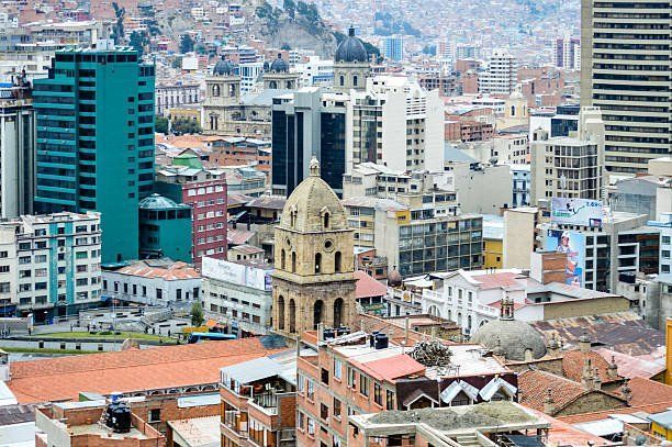 Cityscape of La Paz, Bolivia, with diverse buildings, including modern skyscrapers, and traditional architecture. The scene is a mix of tan, white, and blue hues.