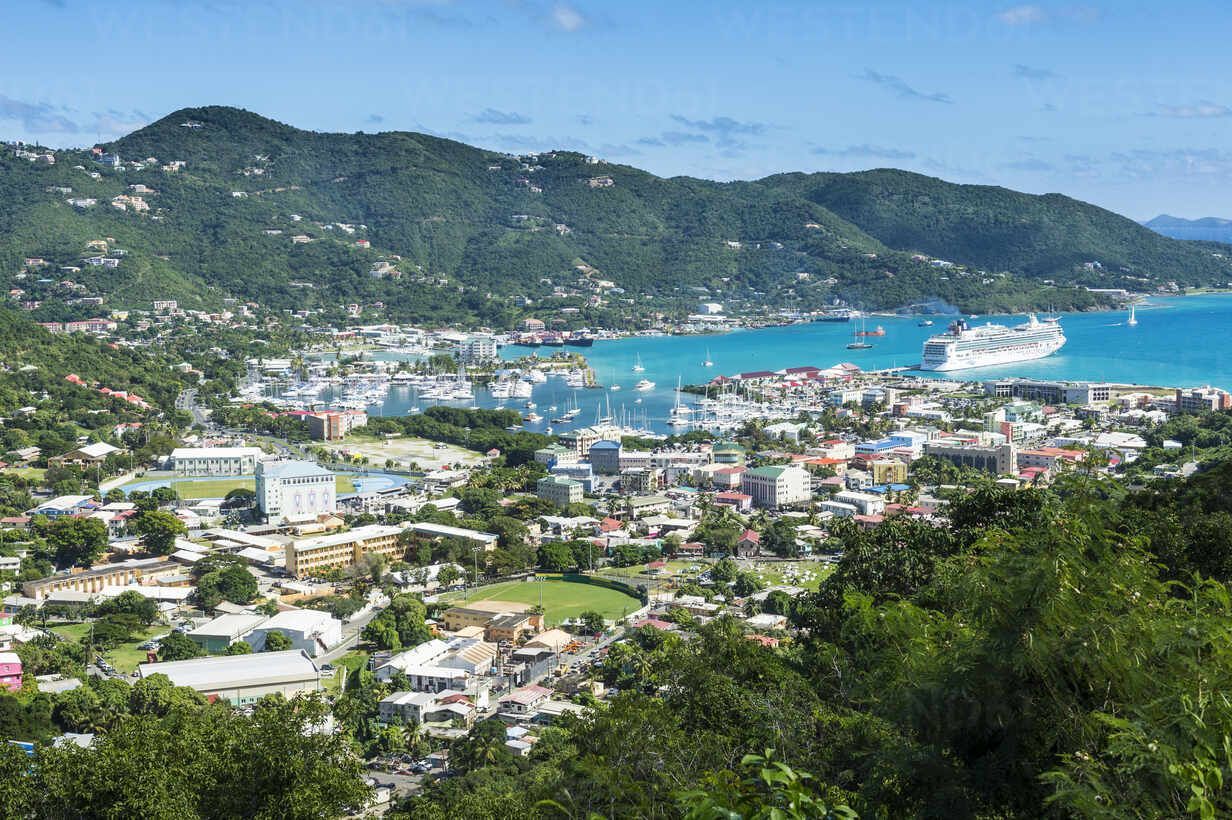 Overlooking a harbor town, with lush green mountains, turquoise water, and a cruise ship.