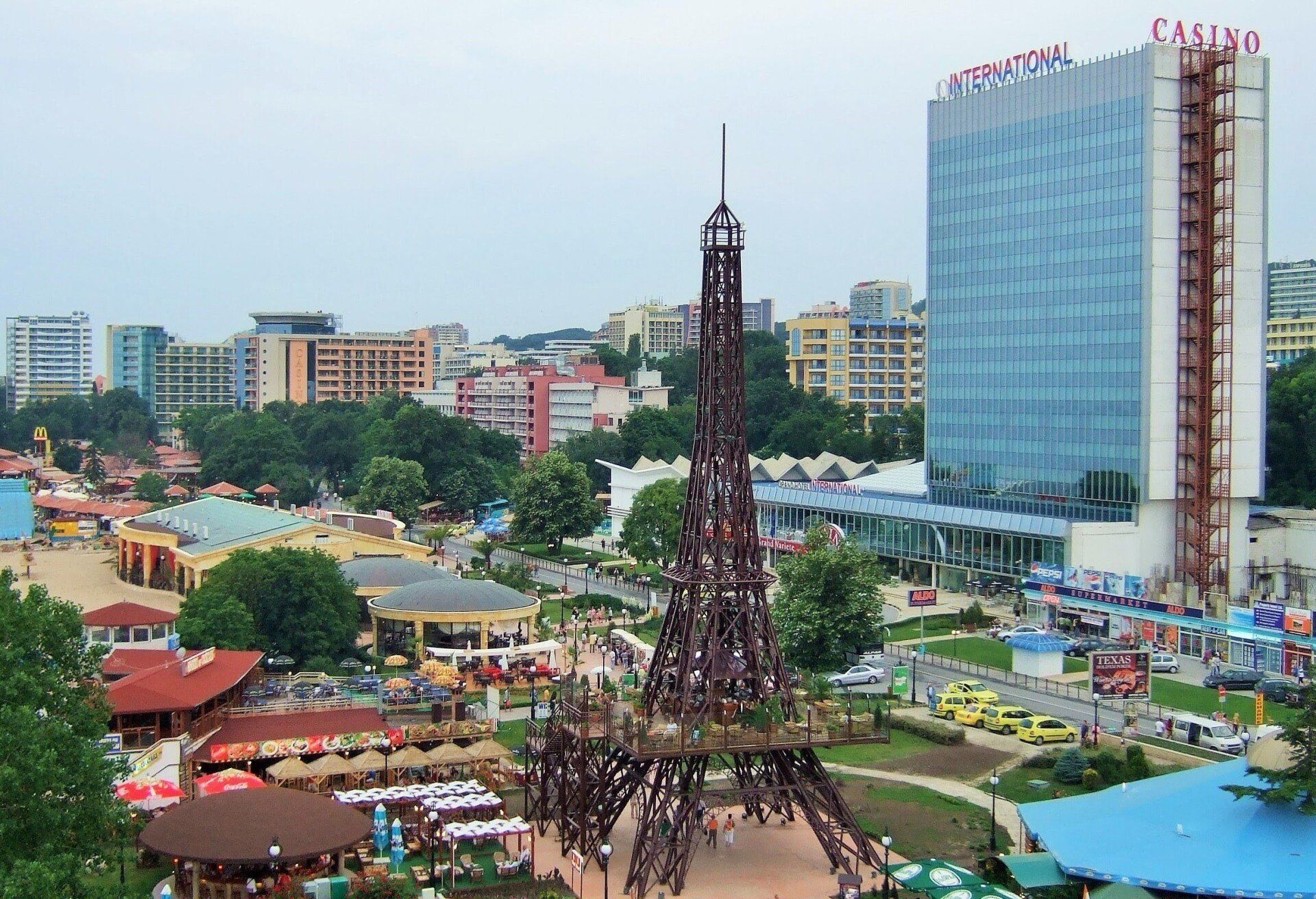A cityscape with a replica Eiffel Tower, buildings, and a casino. Trees and a cloudy sky provide a backdrop.